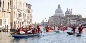 Kerstmannen varen in gondels op Canal Grande tijdens overstroming Venetië