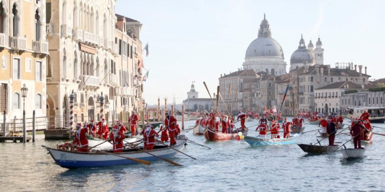 Kerstmannen varen in gondels op Canal Grande tijdens overstroming Venetië