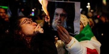 Demonstranten steken sigaretten aan met foto van Khamenei als daad van ongehoorzaamheid